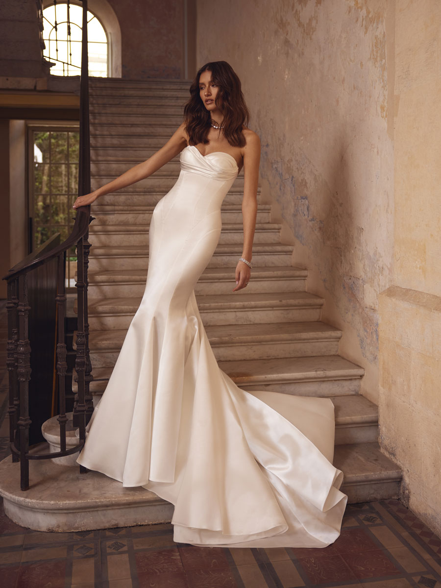 Love Couture Bridal Wedding Dresses. Woman in intricate wedding dresses near historical stone steps.