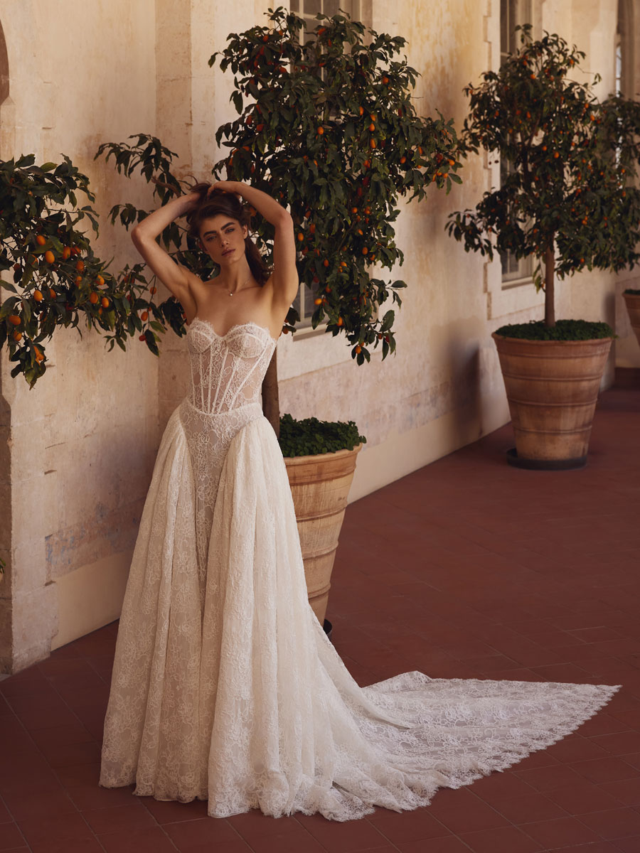 Contemplative bride in lace wedding dresses at historical ruins.