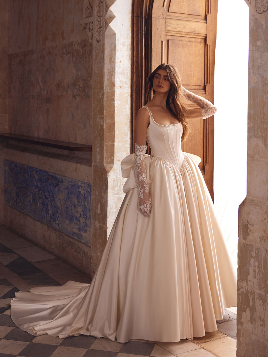 Love Couture Bridal Wedding Dresses. Bride in off-the-shoulder wedding dresses by ancient stone steps.