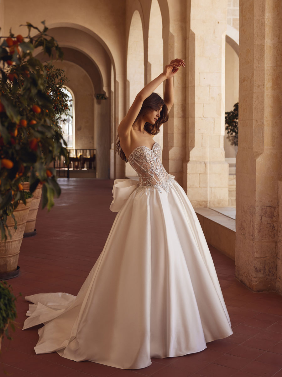 Love Couture Bridal Wedding Dresses Woman in a lace wedding dress near ancient stone columns.