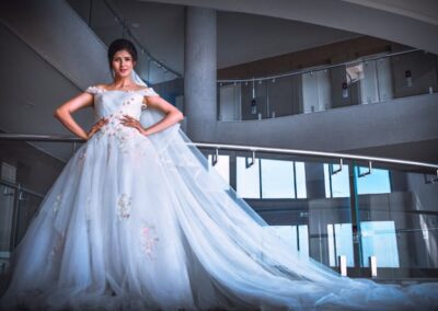 A bride in an elegant wedding dress poses gracefully on a staircase, highlighting the elegance found in Bridal Gown Stores.