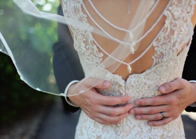 A couple in wedding attire holds hands, symbolizing their bond, with stunning bridal gowns elegantly displayed from Bridal Gown Stores nearby.