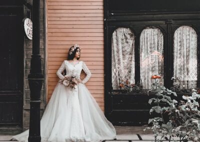 A woman in a wedding dress stands gracefully outside the Bridal Gown Stores, showcasing elegance and anticipation for her special day.